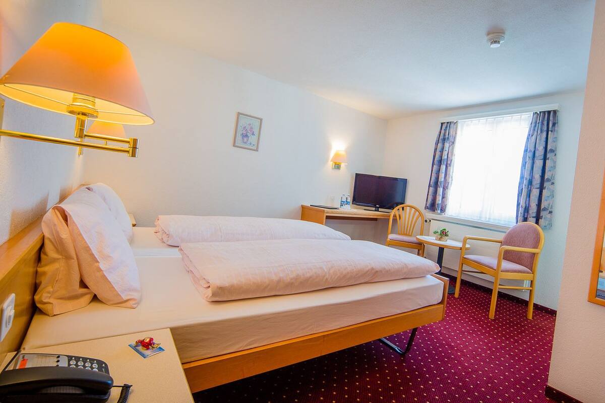 Une chambre d’hôtel avec deux lits, un bureau, une chaise, une télévision et un téléphone.
