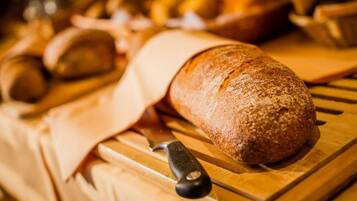 A loaf of bread on a wooden cutting board with a knife.