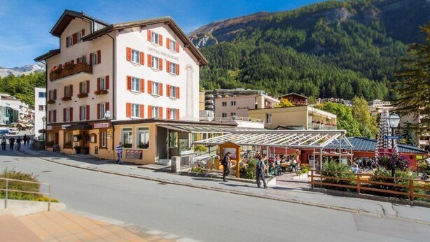 A hotel with multiple floors, outdoor seating, and a mountain backdrop. - Hotel Heilquelle (Leukerbad)