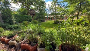 A lush garden with various plants and a thatched-roof structure. - Kräuterhotel Heidejäger (Rotenburg)