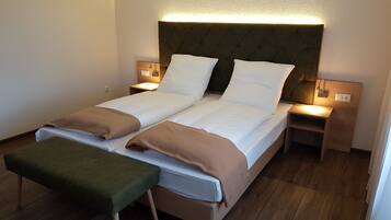 A double bed with two nightstands, a bench, and a headboard with integrated lighting.