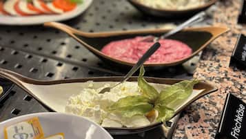 A buffet with various dishes, including salads, meats, and cheeses, arranged on a granite countertop.