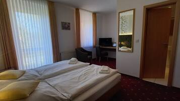A hotel room with two beds, a desk, a television, and a mirror.