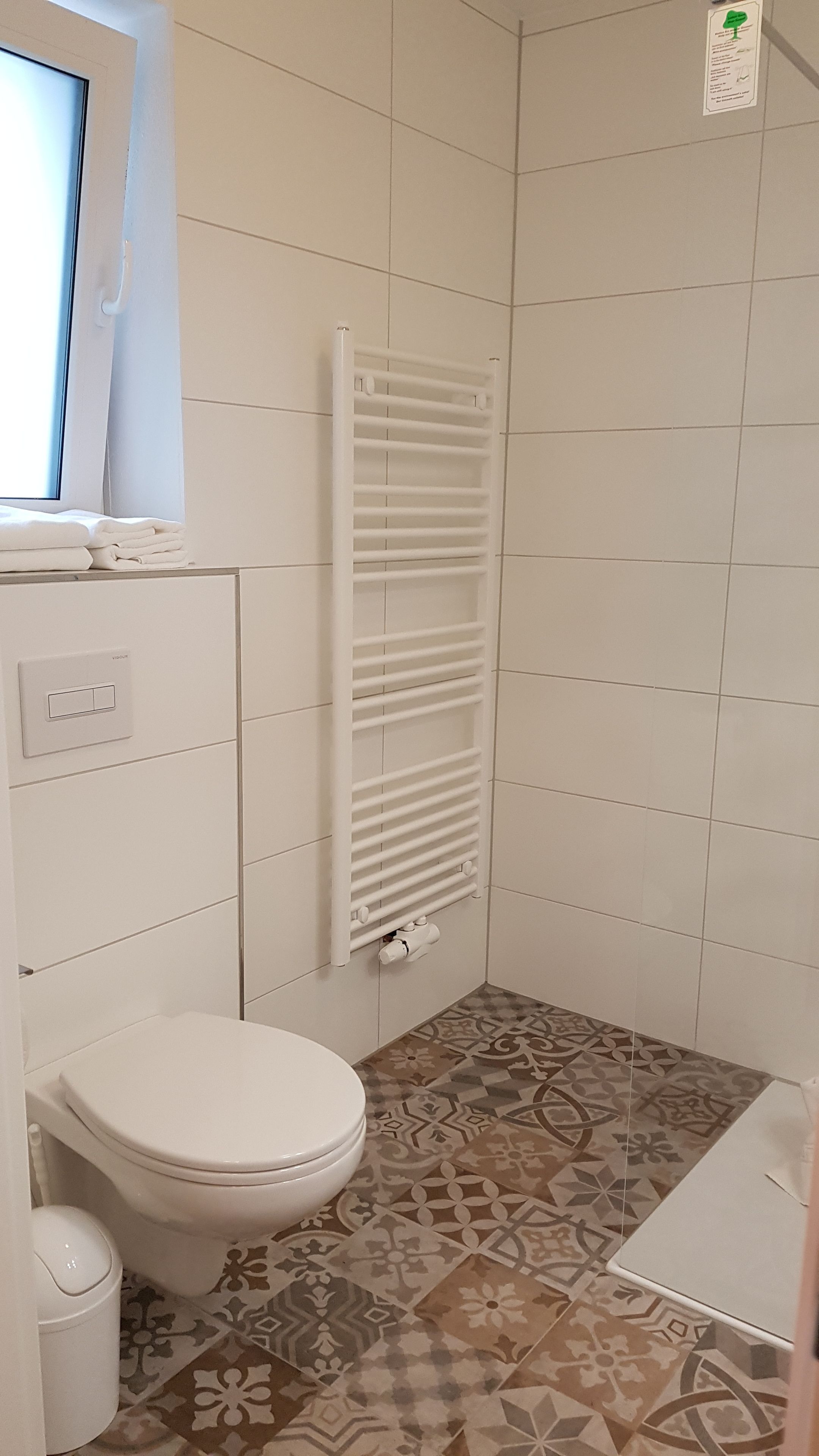 Un baño pequeño con inodoro, toallero y zona de ducha.
