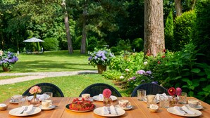 Une table à manger installée à l’extérieur, avec des assiettes, des tasses et un dessert.