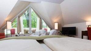 Une chambre d’hôtel moderne dotée d’un grand lit, d’une télévision et d’un balcon offrant une vue sur les arbres.