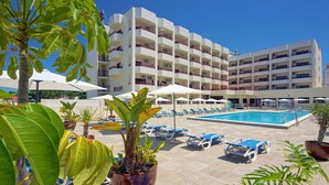 Un hotel con piscina, varios balcones y zonas de estar al aire libre con sombrillas.