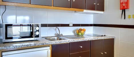 A kitchen with a microwave, sink, and cabinets.