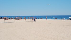 Una playa con sombrillas y gente.