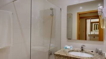 Un baño con cabina de ducha de vidrio, lavabo de granito y un espejo que refleja una puerta y la zona del lavabo.