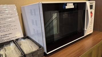 A microwave oven on a wooden counter with a safety instruction manual beside it.