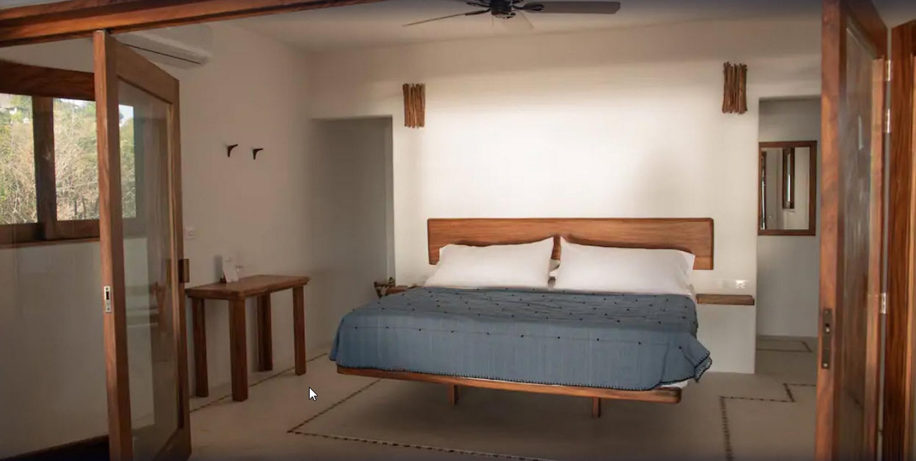Un dormitorio con cama, una mesita y un ventilador de techo.