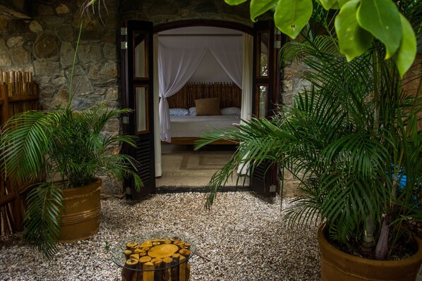 Una habitación con una cama, una pared de piedra y plantas en macetas.