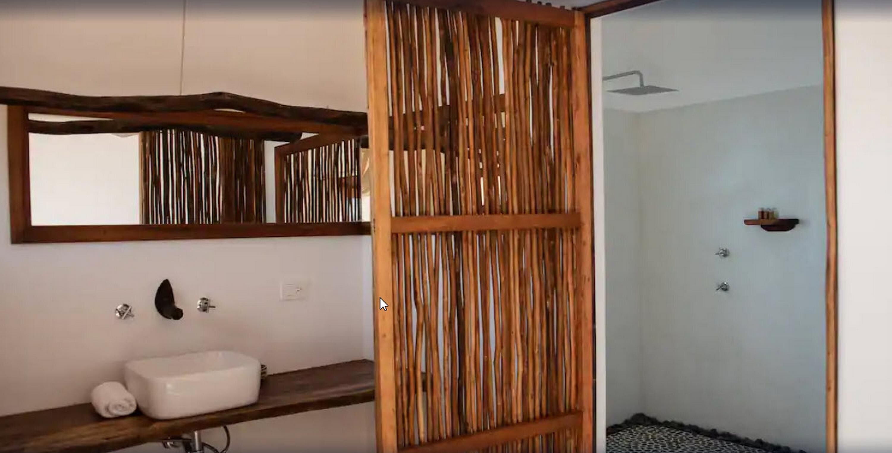 A bathroom with a wooden slat partition, a white sink, and a mirror above it.