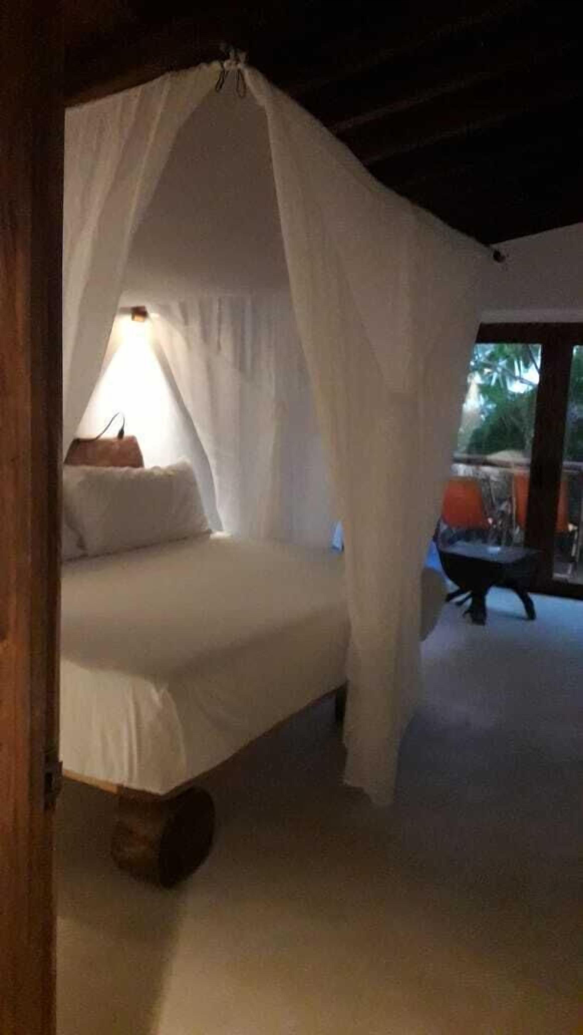 Ein Bett mit Baldachin in einem Zimmer mit Blick ins Freie.