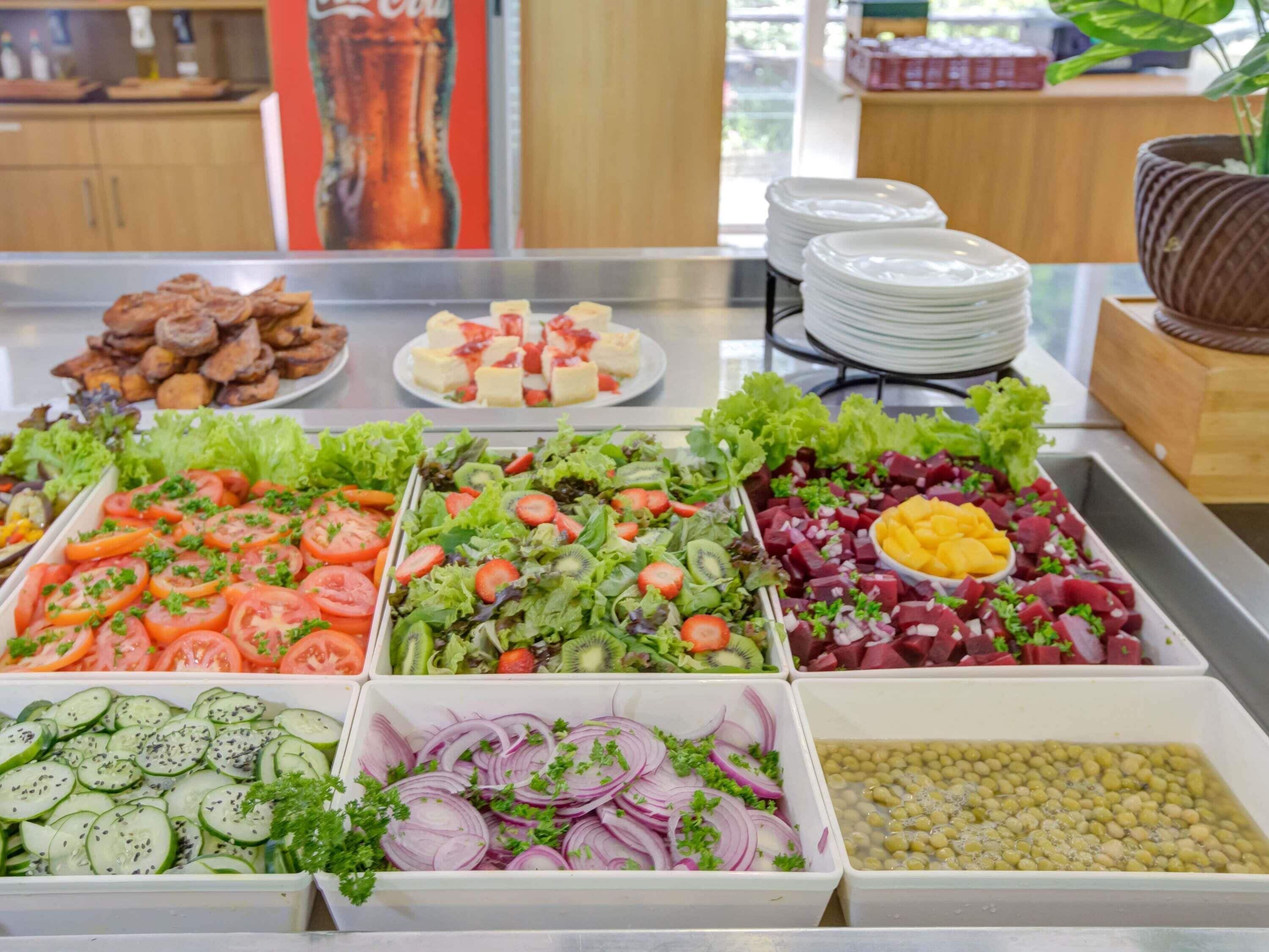 Un bufé con diversas opciones de comida, incluyendo ensaladas, frutas y otros platos.