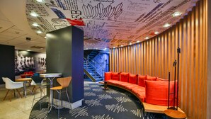 Un interno moderno con una zona salotto dalle linee curve, una scala e una parete con decorazioni astratte.