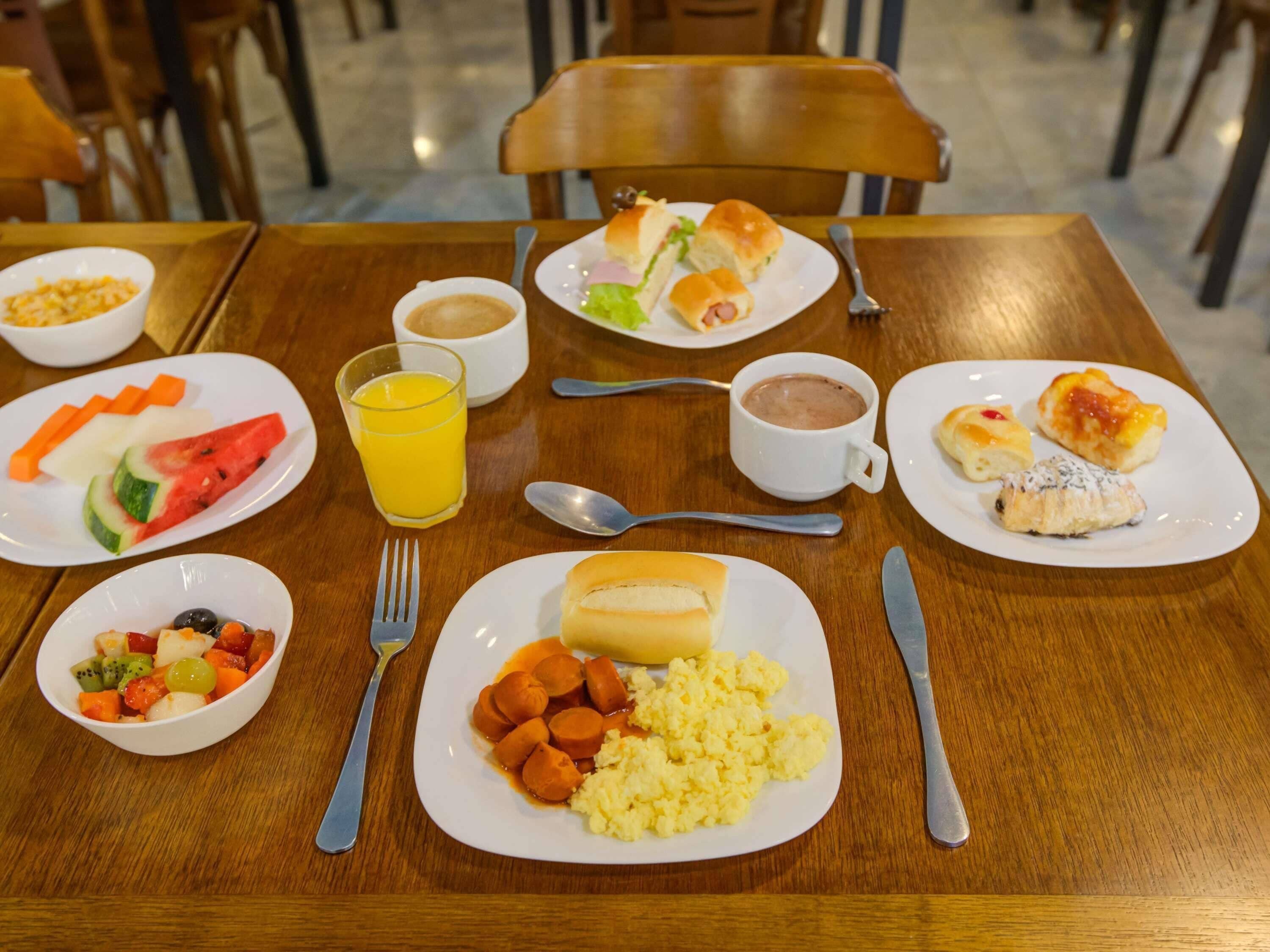 A dining table with plates of food, a glass of orange juice, and a cup of coffee.