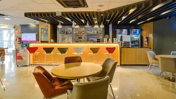Zona de bar moderna con mostrador, taburetes y una mesa redonda con sillas.