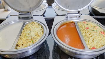 Two electric griddles with pasta dishes, one with a creamy sauce and the other with a tomato-based sauce.
