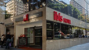 Esterno dell'hotel ibis con ingresso visibile, insegna e riflessi degli edifici circostanti.