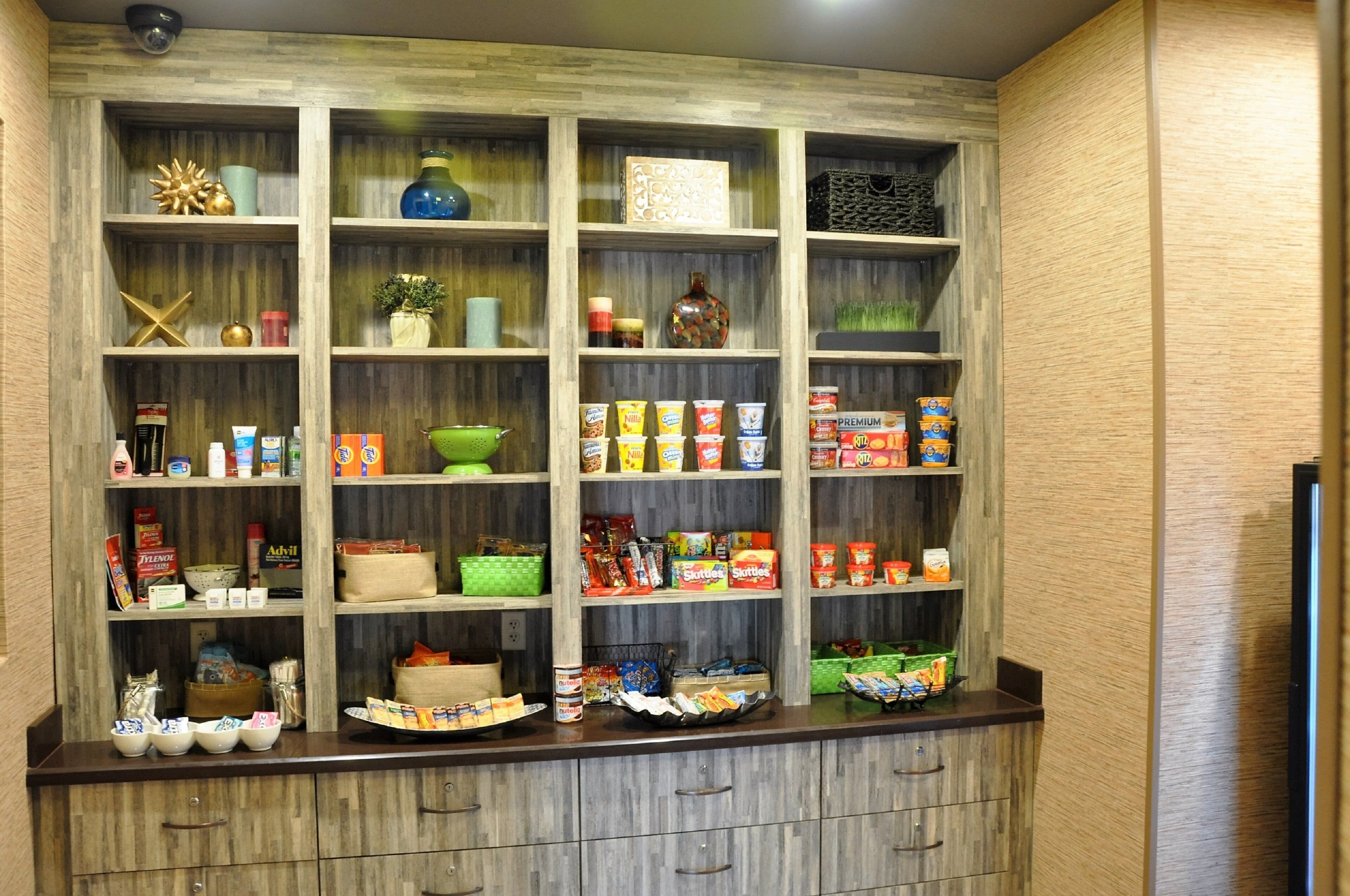 A kitchen with wooden cabinets and shelves containing various food items and kitchenware.