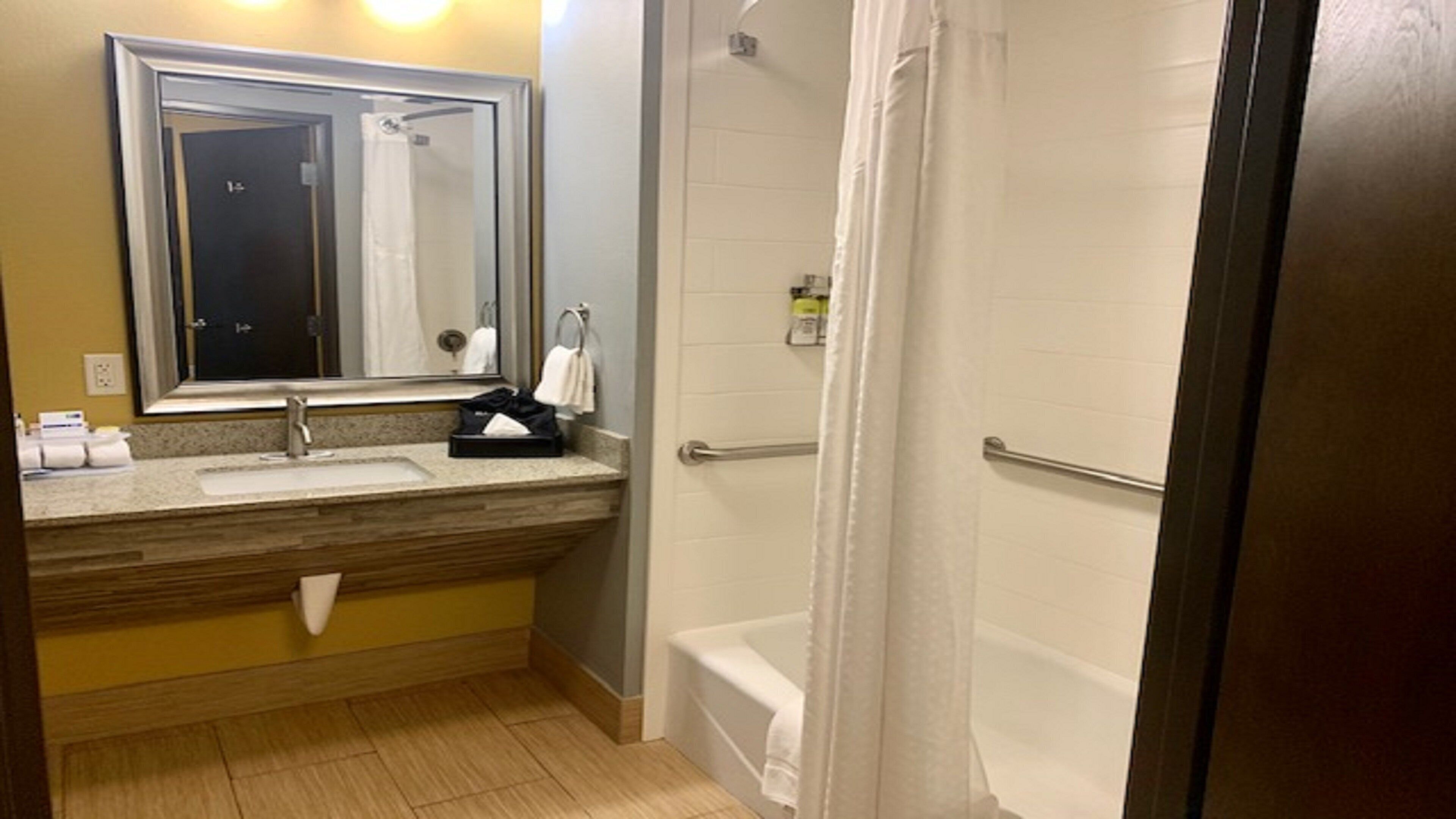Un baño con lavamanos, espejo, toallero y zona de ducha con cortina.