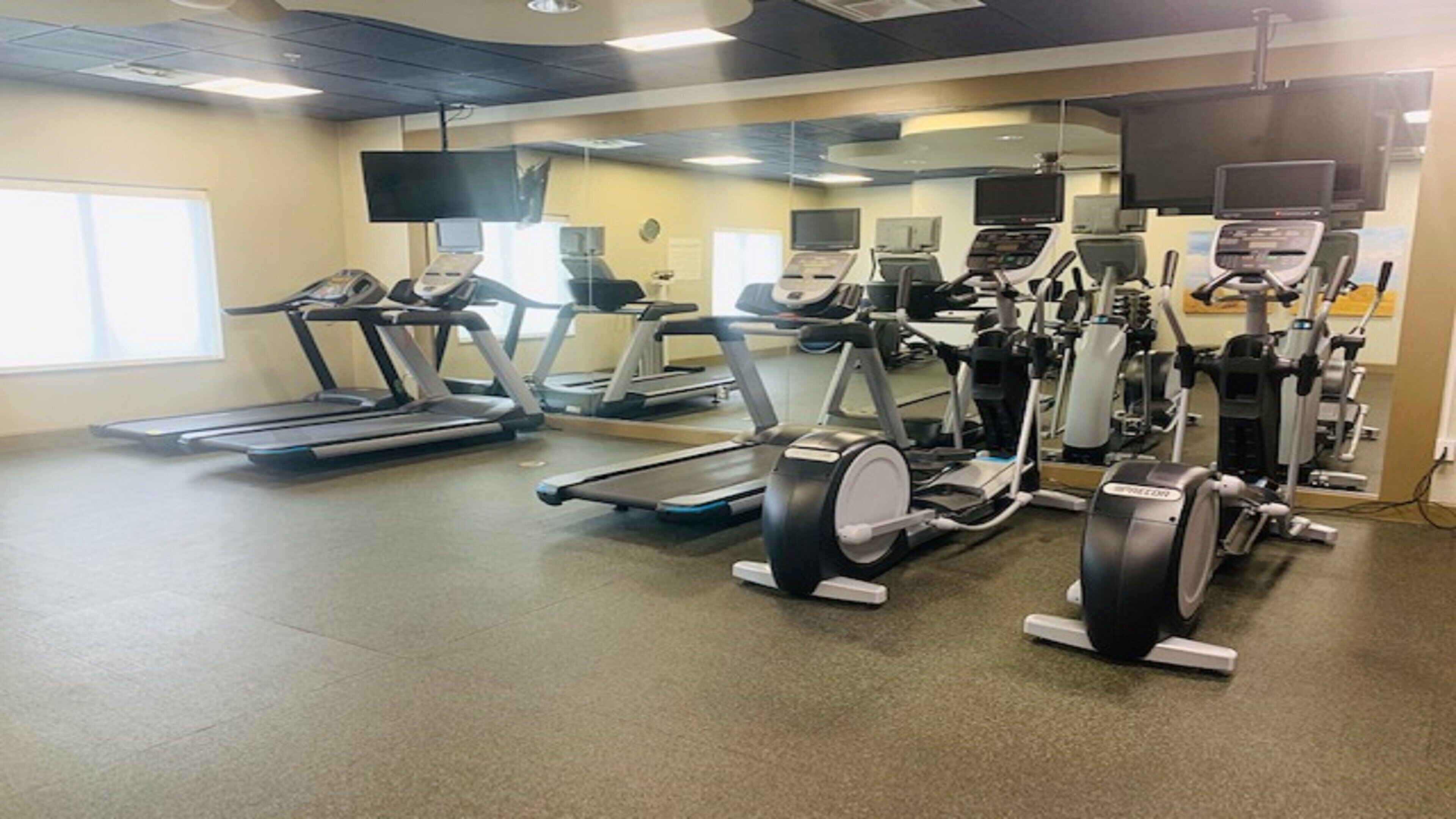 Ein Fitnessstudio mit Laufbändern, Crosstrainern und Gewichtsmaschinen.