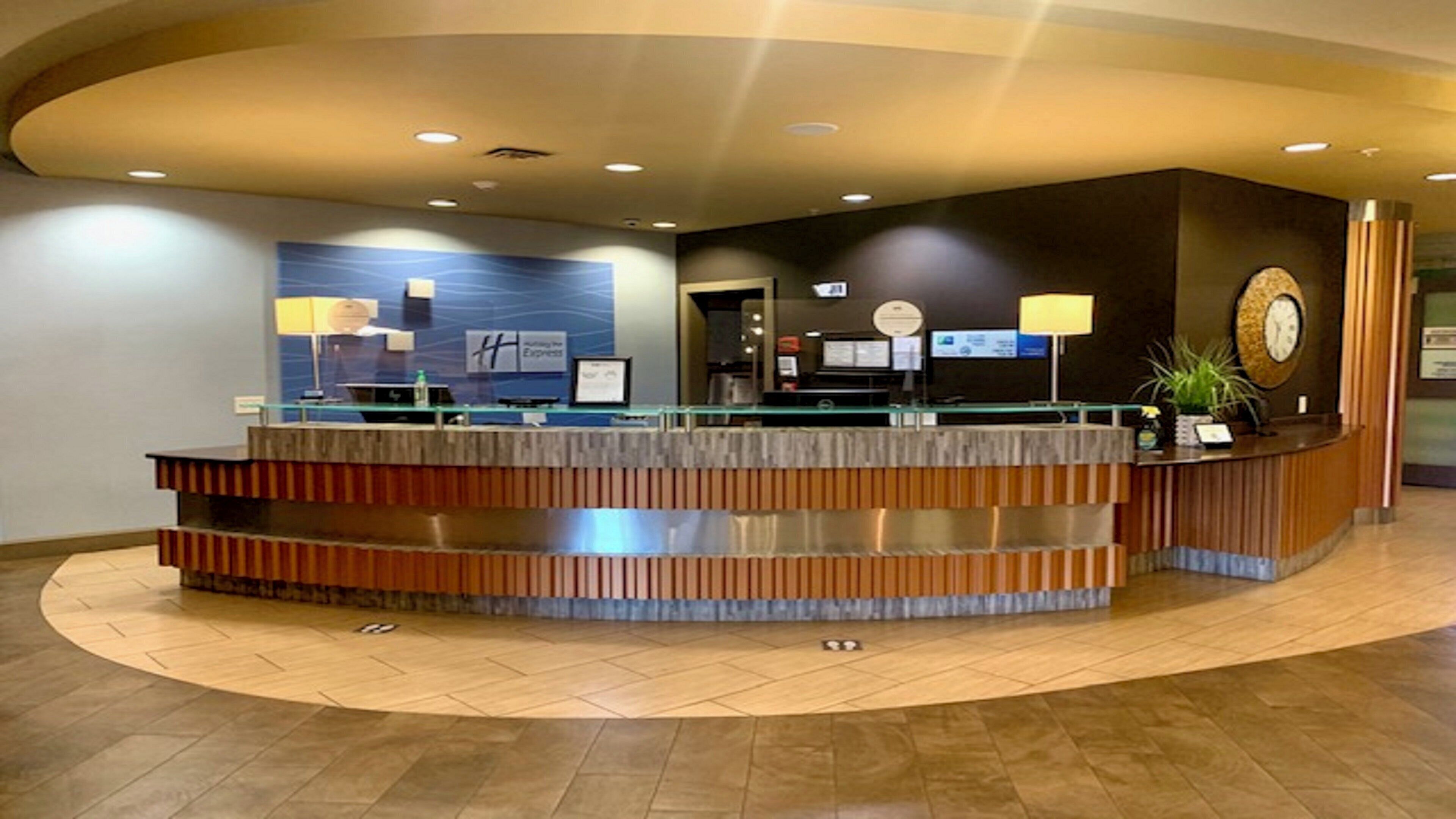 A reception desk with a curved design, multiple monitors, and a clock on the wall.