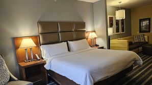 A hotel room with a large bed, two bedside tables with lamps, a sofa, and a small round table. - Holiday Inn Express & Suites Perry-National Fairground Area, an IHG Hotel (Perry)