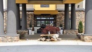 A building entrance with stone facade, large columns, and a covered entrance area. - Holiday Inn Express & Suites Perry-National Fairground Area, an IHG Hotel (Perry)