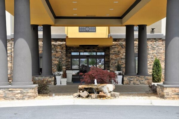 A building entrance with stone facade, large columns, and a covered entrance area. - Holiday Inn Express & Suites Perry-National Fairground Area, an IHG Hotel (Perry)