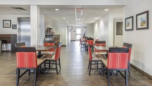 Un grand espace dédié à la restauration, avec plusieurs tables et chaises, un distributeur automatique et un escalier menant à un niveau supérieur.