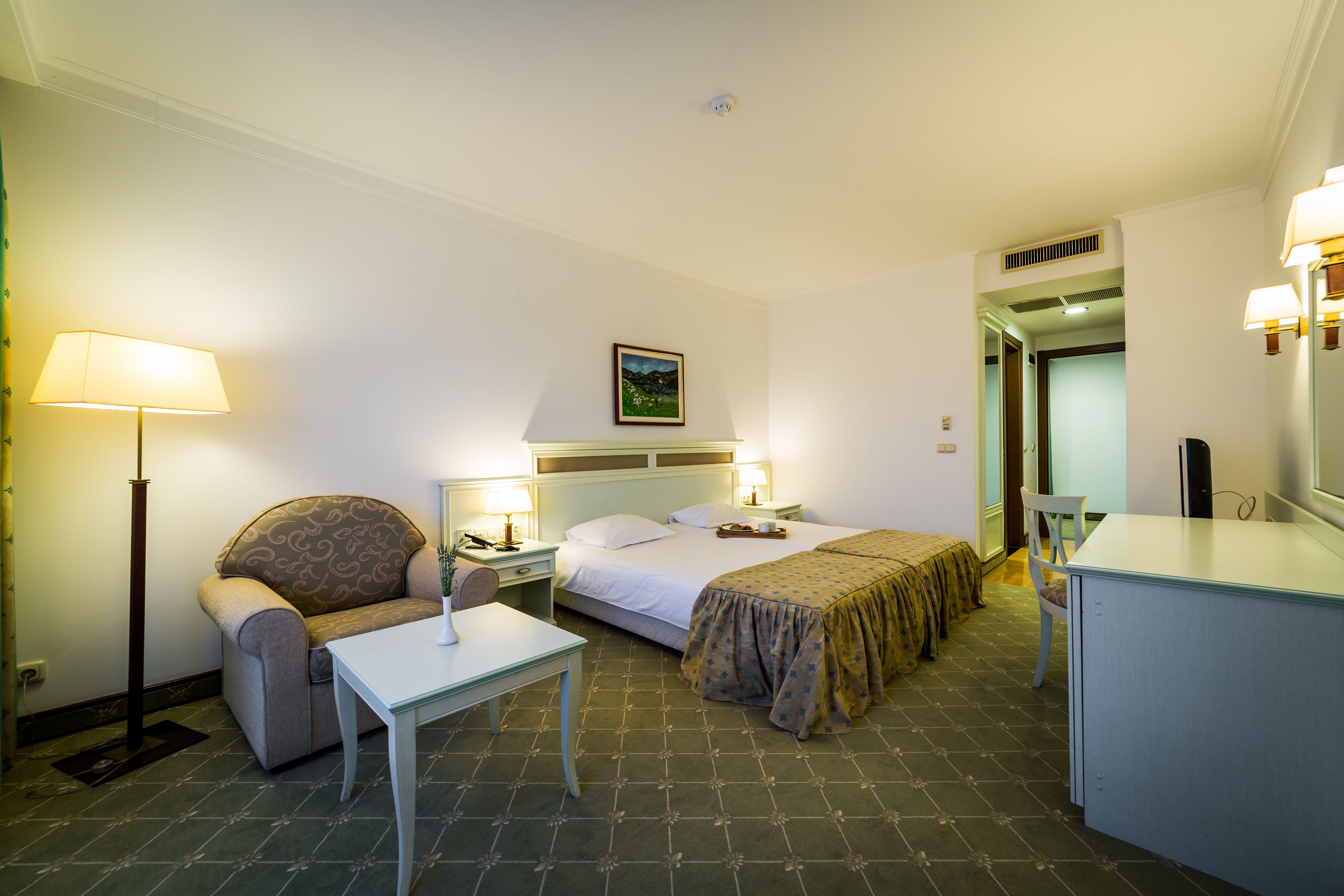 A hotel room with a bed, a sofa, a desk, and a chair.