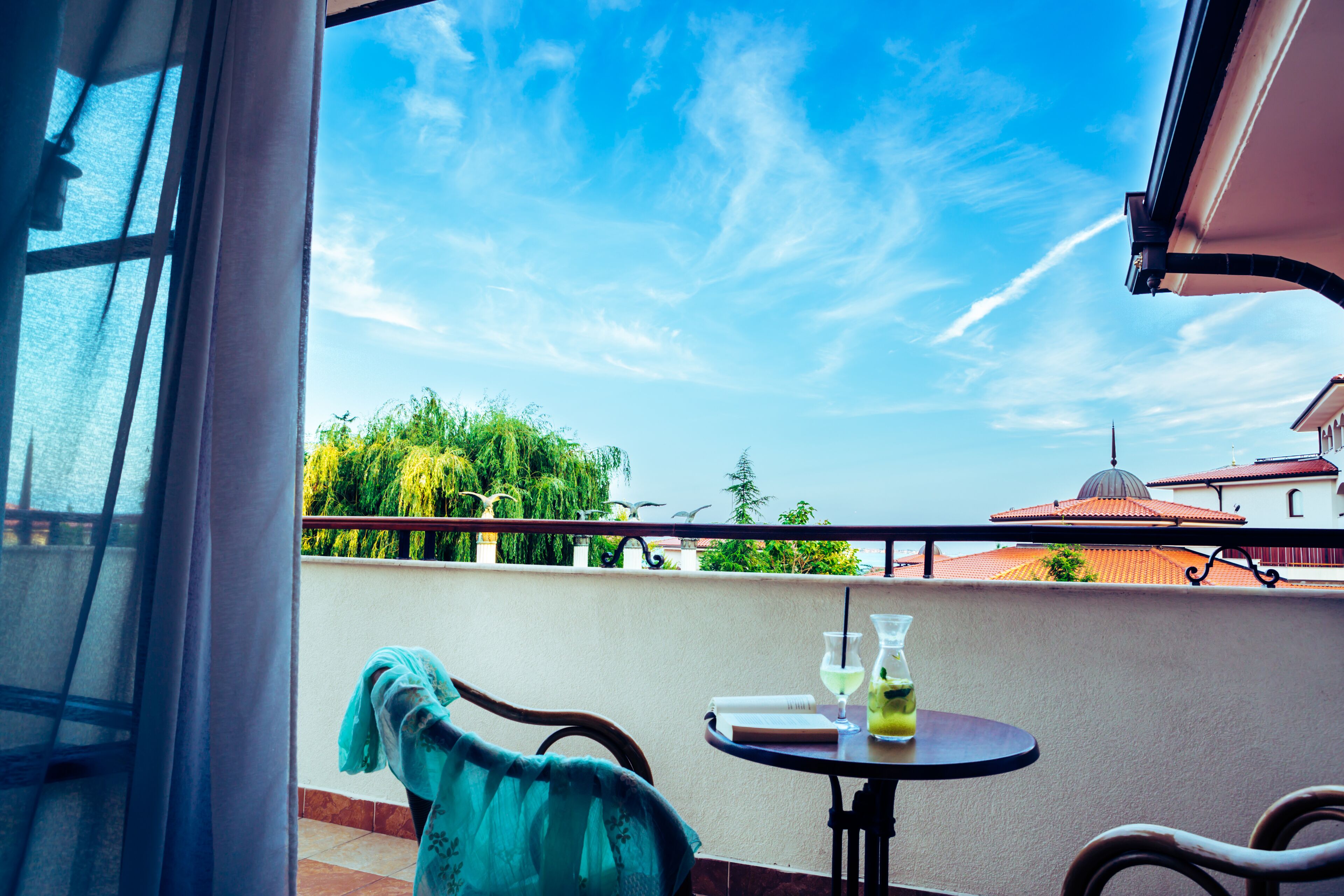 Ein Balkon mit Tisch, Stuhl und Blick auf Grünflächen und Gebäude.