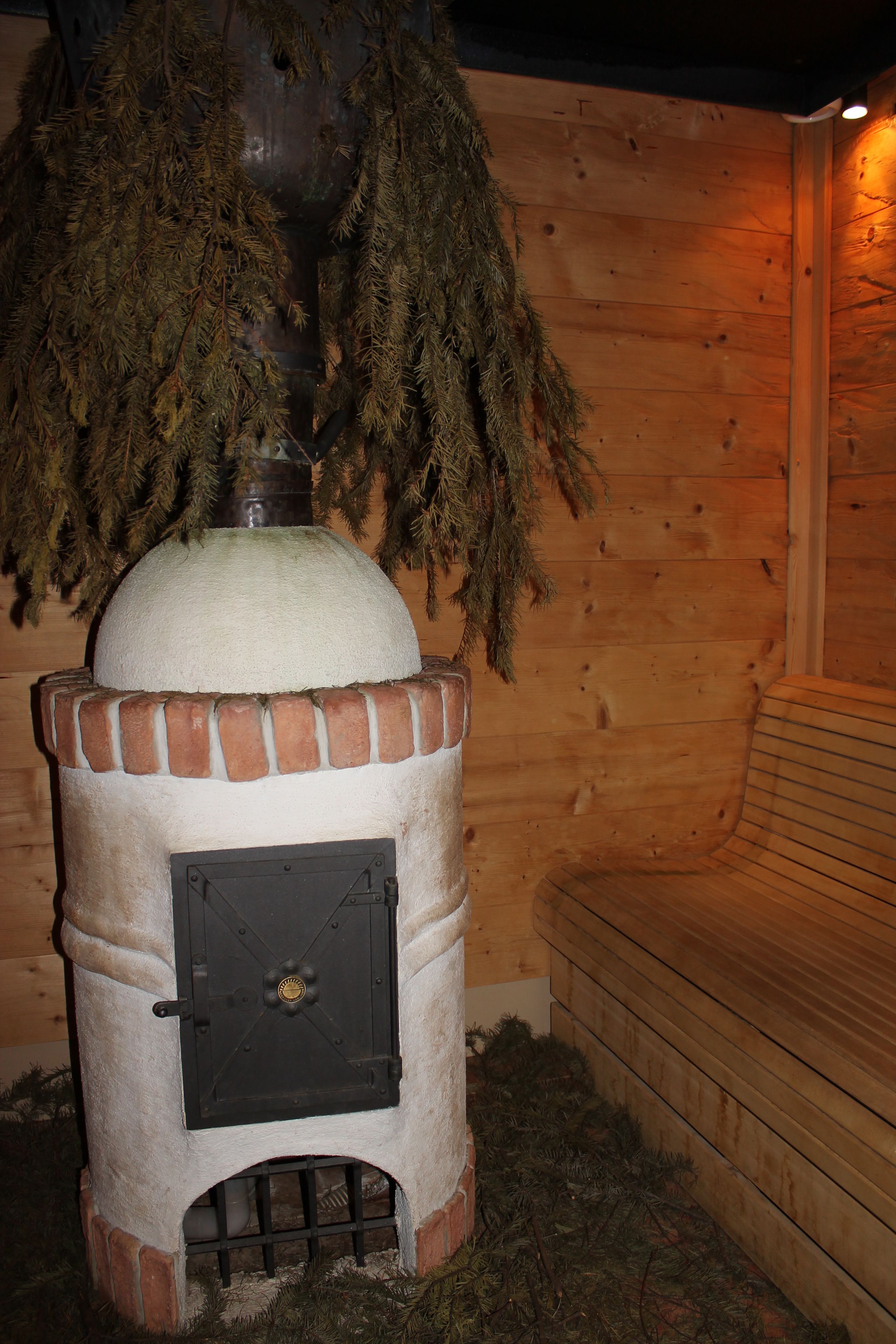 A wood-burning stove with a chimney, surrounded by wooden walls and a bench.
