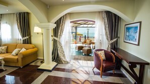A hotel lobby with a sofa, armchair, and a view of the sea through an arched doorway. - Helena VIP Villas and Suites (Sunny Beach)
