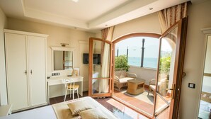 A bedroom with a bed, a desk, a chair, and a balcony with a view of the sea. - Helena VIP Villas and Suites (Sunny Beach)