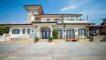 A two-story house with a large front porch, stone facade, and multiple windows.
