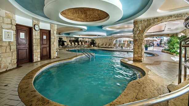 A large indoor swimming pool with a stone wall and a wooden ceiling. - Four Seasons Country Club (Loulé)