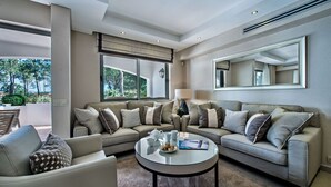 A modern living room with two sofas, a coffee table, and a large window offering a view of trees. - Four Seasons Country Club (Loulé)