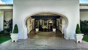 A grand entrance with an arched doorway, potted plants, and a tiled floor. - Four Seasons Country Club (Loulé)