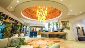 A hotel lobby with a reception desk, seating area, and a unique circular ceiling design. - Four Seasons Country Club (Loulé)