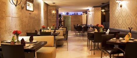 Un restaurante con varias zonas de comedor, incluyendo cabinas y mesas, con una decoración interior cálida y detalles de madera.