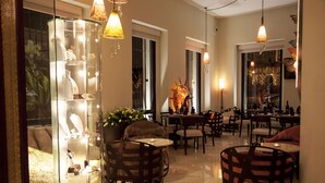 A well-lit, spacious lounge area with multiple seating options, including round tables and chairs, and a glass display case with jewelry.