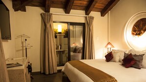 A hotel room with a bed, a desk, a mirror, and a window with curtains.