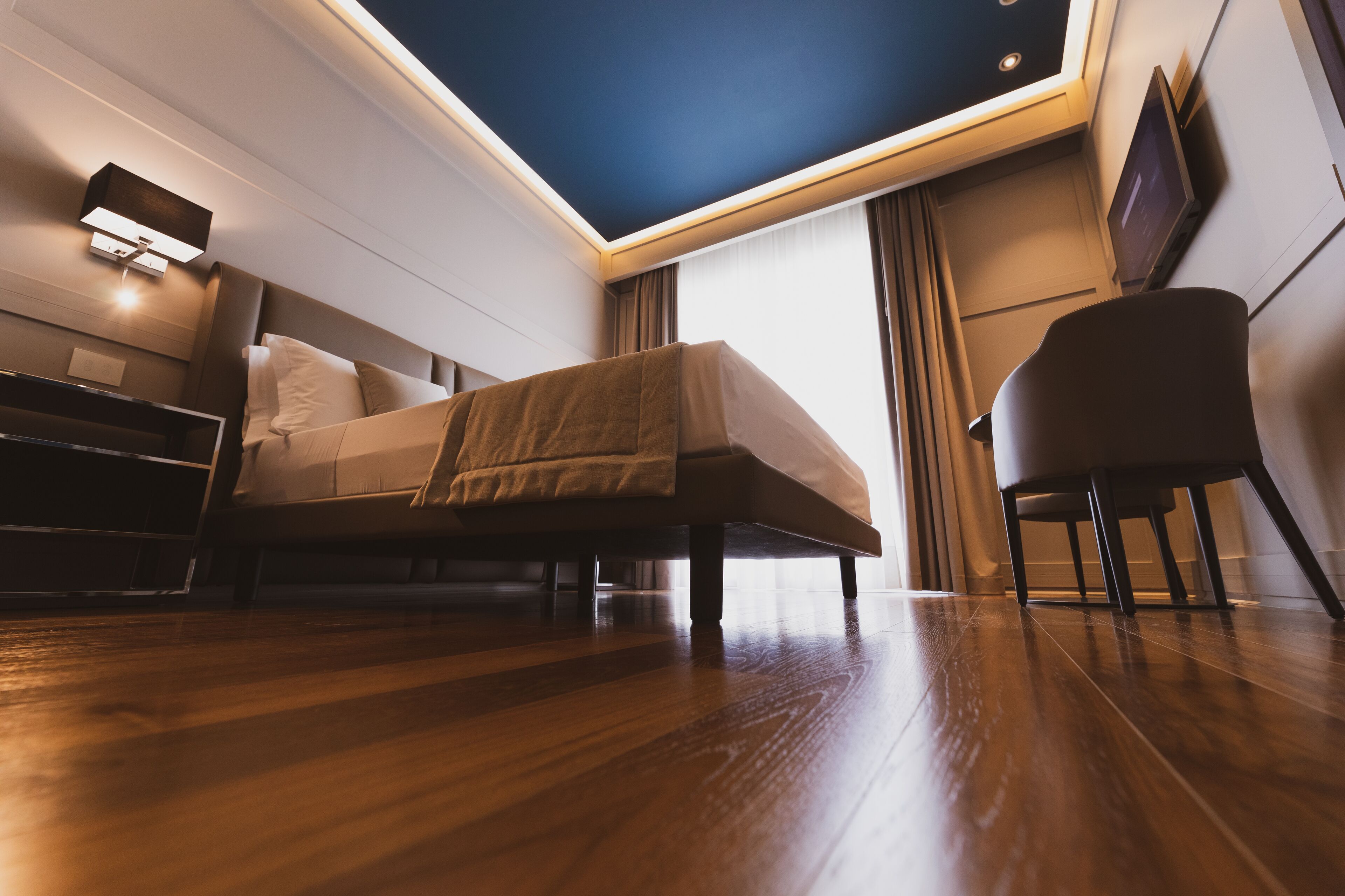 Una habitación de hotel moderna con una cama, un escritorio, una silla y un ventanal grande.