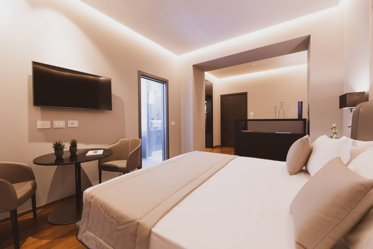 Ein modernes Hotelzimmer mit Bett, Fernseher, Schreibtisch und Stuhl.