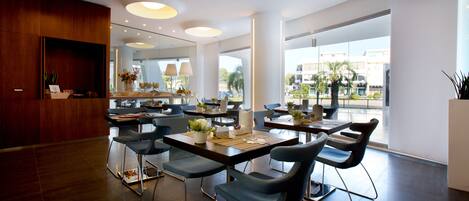 A modern hotel lobby with a reception desk, seating area, and large windows offering a view of the city.