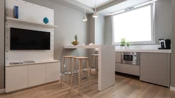 A modern kitchen with wooden stools, a built-in microwave, and a large window.